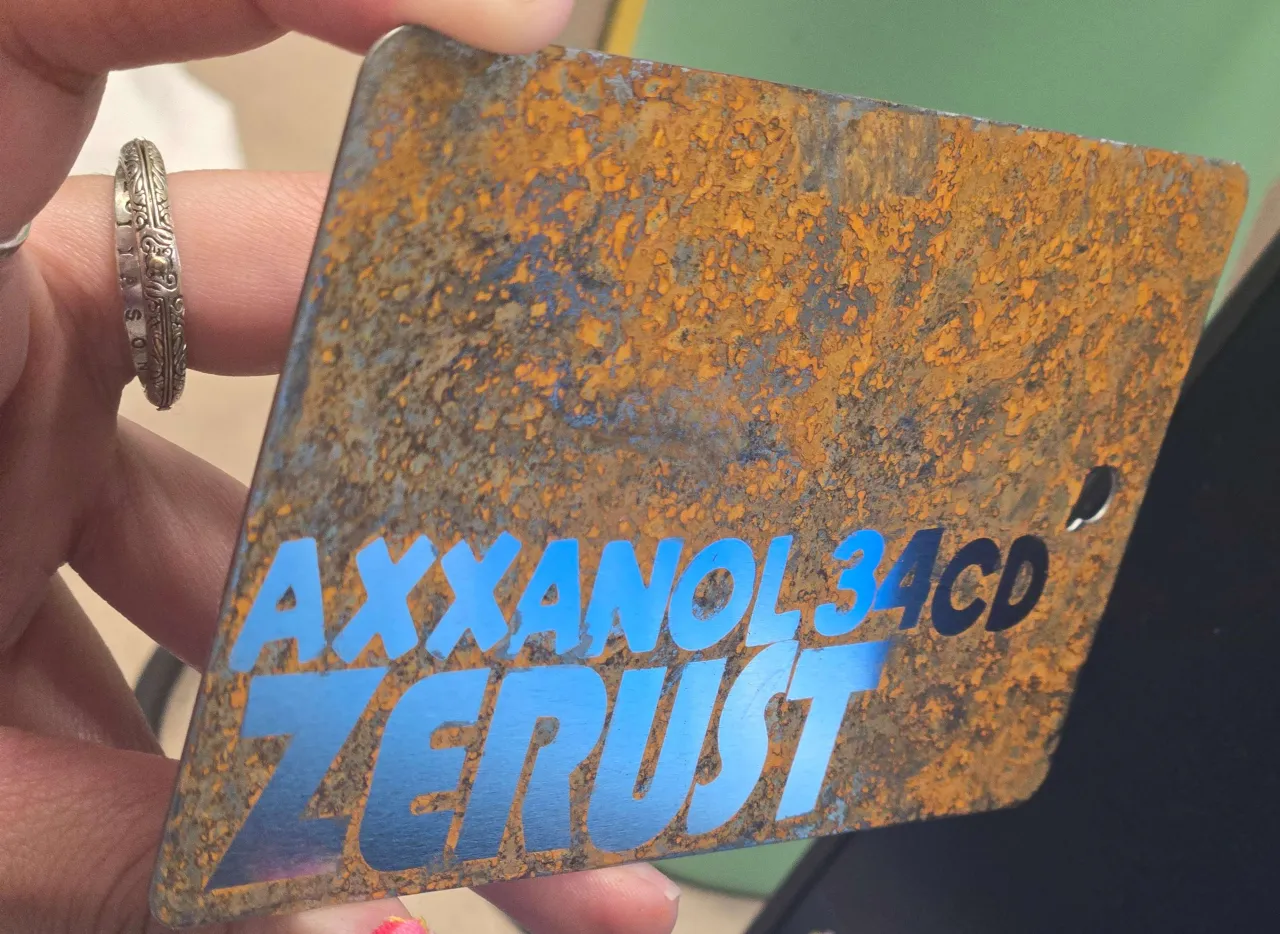 Hand holding a rusted Zerust Axxanol test panel at the show